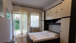 A bedroom with a bed, a wardrobe, a radiator, and a window with curtains. - Charming Apartment on Croatian Islands (Malinska-Dubasnica)