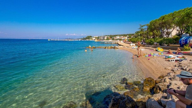 A beach with clear water, rocky shoreline, and people sunbathing. - Charming Apartment on Croatian Islands (Malinska-Dubasnica)