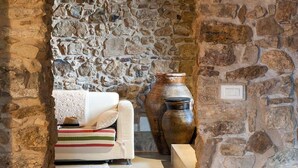 Una habitación con paredes de piedra, un sofá, un florero grande y una mesita pequeña.
