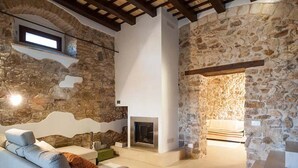 Una sala de estar acogedora con pared de piedra, chimenea y sofá.