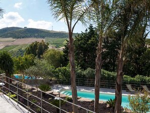 A pool area with a view of a vineyard and hills in the background. - Belvilla by OYO Maranzano Marietta (Buseto Palizzolo)