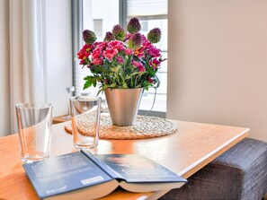 A wooden table with a metal pot of flowers, two glasses, and an open book. - Frisch Renovierte Wohnung im Zentrum von Wismar (Wismar)