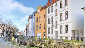 A row of colorful buildings along a cobblestone street with a stone wall and a small bridge. - Frisch Renovierte Wohnung im Zentrum von Wismar (Wismar)