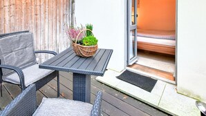 A patio with wicker furniture, a wicker basket with plants, and a sliding glass door leading to a bedroom. - Frisch Renovierte Wohnung im Zentrum von Wismar (Wismar)
