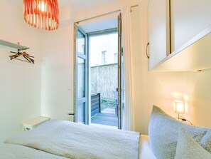 A bedroom with a bed, a hanging light fixture, a bedside table, and a view of the outside. - Frisch Renovierte Wohnung im Zentrum von Wismar (Wismar)