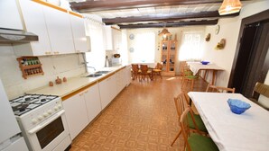 Una cocina con armarios blancos, estufa y comedor con mesa y sillas.