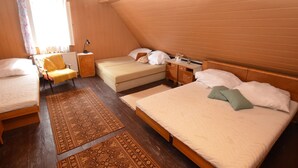 Una habitación con dos camas, una silla, una mesita de noche y un ventanal con cortinas.