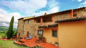 A stone building with a tiled roof, a balcony, and a view of the countryside.