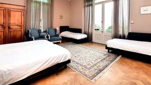 A hotel room with two beds, a chandelier, a patterned rug, and a view of the outdoors. - Spacious Pet-friendly Castle in Stavelot (Stavelot)