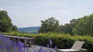 A patio with outdoor seating, surrounded by lavender and greenery, overlooking a hilly landscape. - Spacious Pet-friendly Castle in Stavelot (Stavelot)