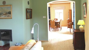 Una sala de estar con chimenea, un comedor con mesa y sillas, y un pasillo que conduce a otra habitación.