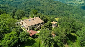 A stone building with a tiled roof surrounded by lush greenery and hills in the background. - Belvilla by Oyo Azalea in Gubbio (Gubbio)