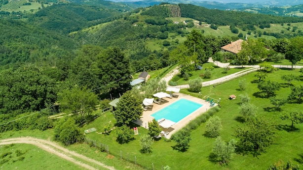 A large swimming pool surrounded by lush green fields and a mountainous backdrop. - Belvilla by Oyo Azalea in Gubbio (Gubbio)
