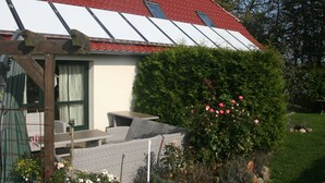 A house with a red roof, a covered porch, and a garden with pink flowers. - Cozy Apartment in Kägsdorf near Sea (Bastorf)