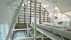 A multi-level interior with a central staircase, seating areas, and a view through a glass wall. - Grand Retreat in Redu (Libin)