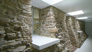 A stone wall interior with a white shelf, skylights, and a visible bathroom area. - Grand Retreat in Redu (Libin)
