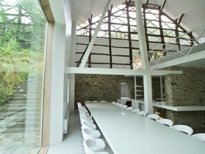A modern interior with a long dining table, white chairs, and a stone wall.