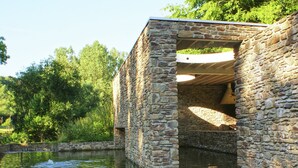 A stone structure partially submerged in water, with a view of surrounding greenery. - Grand Retreat in Redu (Libin)