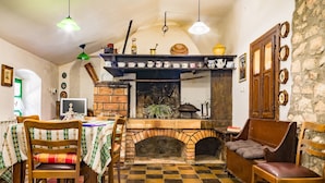 A cozy kitchen with a brick fireplace, wooden furniture, and a checkered floor. - Apartment Crikvenica Near Sandy Beach (Crikvenica)