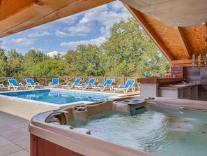Uma área de piscina com duas banheiras de hidromassagem e espreguiçadeiras.