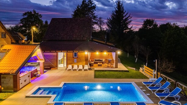 Una piscina con sillas de descanso, un jacuzzi y una terraza de madera.