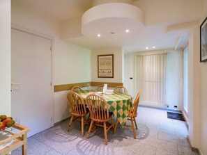 A dining area with a table covered by a checkered tablecloth, surrounded by wooden chairs. - Oostduinkerke Forestside Villa (Koksijde)