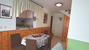 A dining area with a round table covered in a floral tablecloth, surrounded by wooden chairs. - Comfortable Holiday Home Only 500m to the sea With Outdoor Kitchen, Wifi and Airco (Medulin)