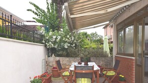 An outdoor patio with a table and chairs, surrounded by potted plants and a stone wall. - Comfortable Holiday Home Only 500m to the sea With Outdoor Kitchen, Wifi and Airco (Medulin)