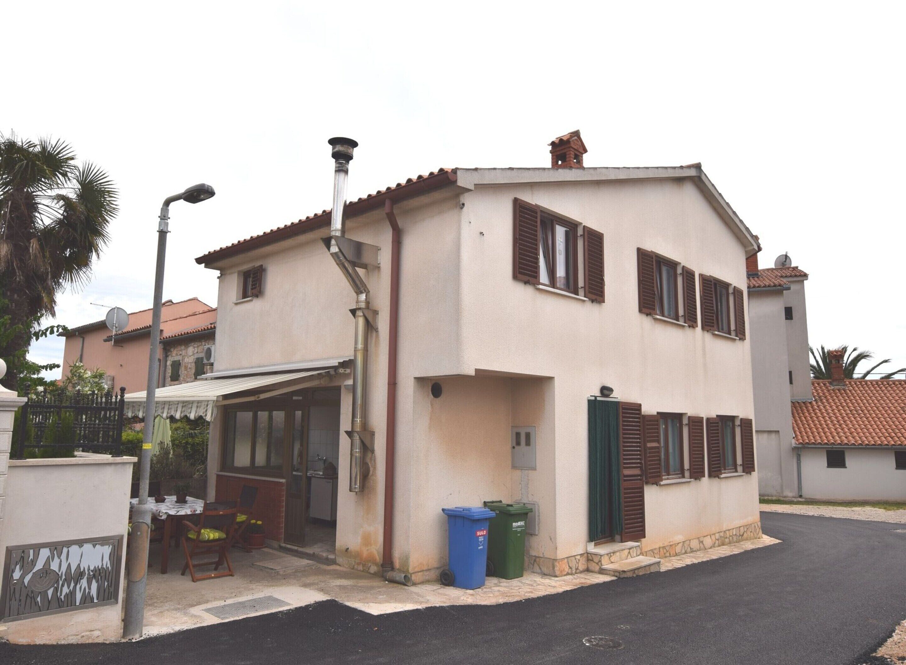 A two-story house with a balcony, a garage, and a street lamp.