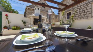 Un espace de restauration en plein air avec des tables préparées pour deux personnes, comprenant des verres à vin, des assiettes et des couverts.