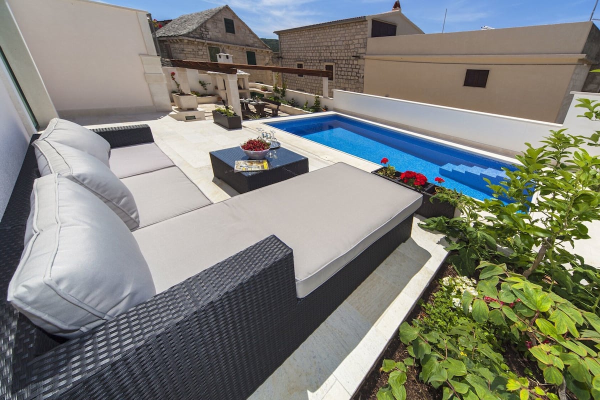 A rooftop patio with a pool, outdoor furniture, and a garden area.