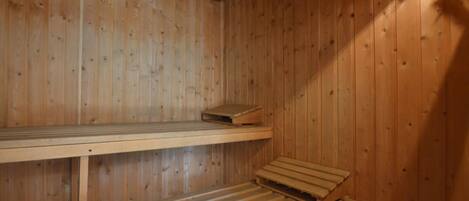 Un sauna en bois avec deux bancs et un banc en bois posé sur le sol.