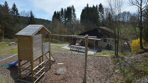 Eine Holzspielanlage mit Rutsche und einem kleinen hausähnlichen Gebäude.