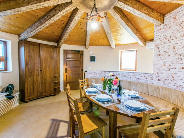 A dining area with wooden tables and chairs, a brick wall, and a wooden ceiling. - Lovely Holiday Home in Fazana With Swimming Pool (Fazana)