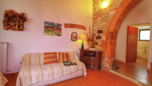A cozy room with a brick wall, a wooden cabinet, a sofa with striped cushions, and a painting on the wall.