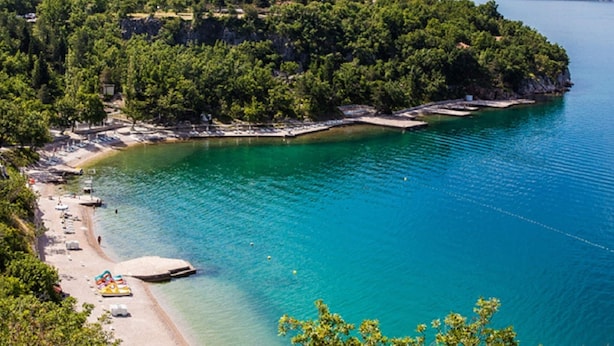 A coastal area with a beach, clear turquoise water, and a forested peninsula. - Charming Home With Swimming Pool and Beautiful Covered Terrace (Crikvenica)
