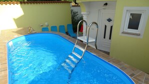 A swimming pool with a ladder, tiled walls, and a door in the background. - Charming Home With Swimming Pool and Beautiful Covered Terrace (Crikvenica)