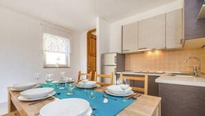 A dining area with a table set for four, a kitchen with modern appliances, and a window with a view. - Charming Home With Swimming Pool and Beautiful Covered Terrace (Crikvenica)