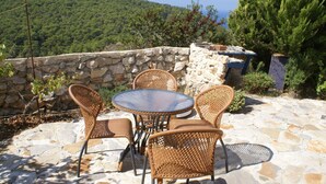 A stone patio with wicker furniture and a stone wall. - Holiday Home With Garden in Kritinia (Rhodes)
