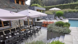 An outdoor dining area with tables and chairs, umbrellas, and a poolside lounge. - Spa Apartment With Private Pool (Spa)