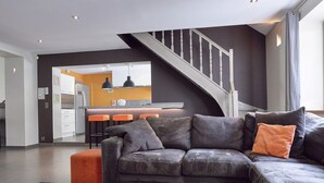 A modern living room with a dark gray sectional sofa, a black coffee table, and a staircase leading to an upper level. - Spa Apartment With Private Pool (Spa)