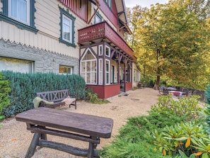 Un bâtiment traditionnel doté d’un banc en bois et d’un chemin de gravier menant à un espace extérieur abrité, aménagé pour s’asseoir.