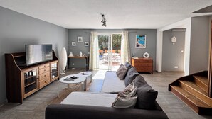 Una sala moderna con sofá, mesa de centro, televisor y mueble de madera.