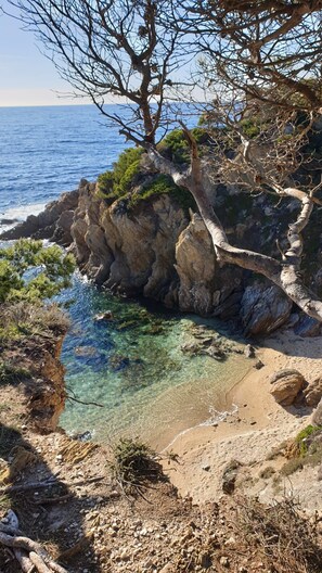 A rocky coastal landscape with clear shallow waters, a sandy beach, and sparse vegetation. - Quiet villa with a large terrace near the Garonne beach (Le Pradet)