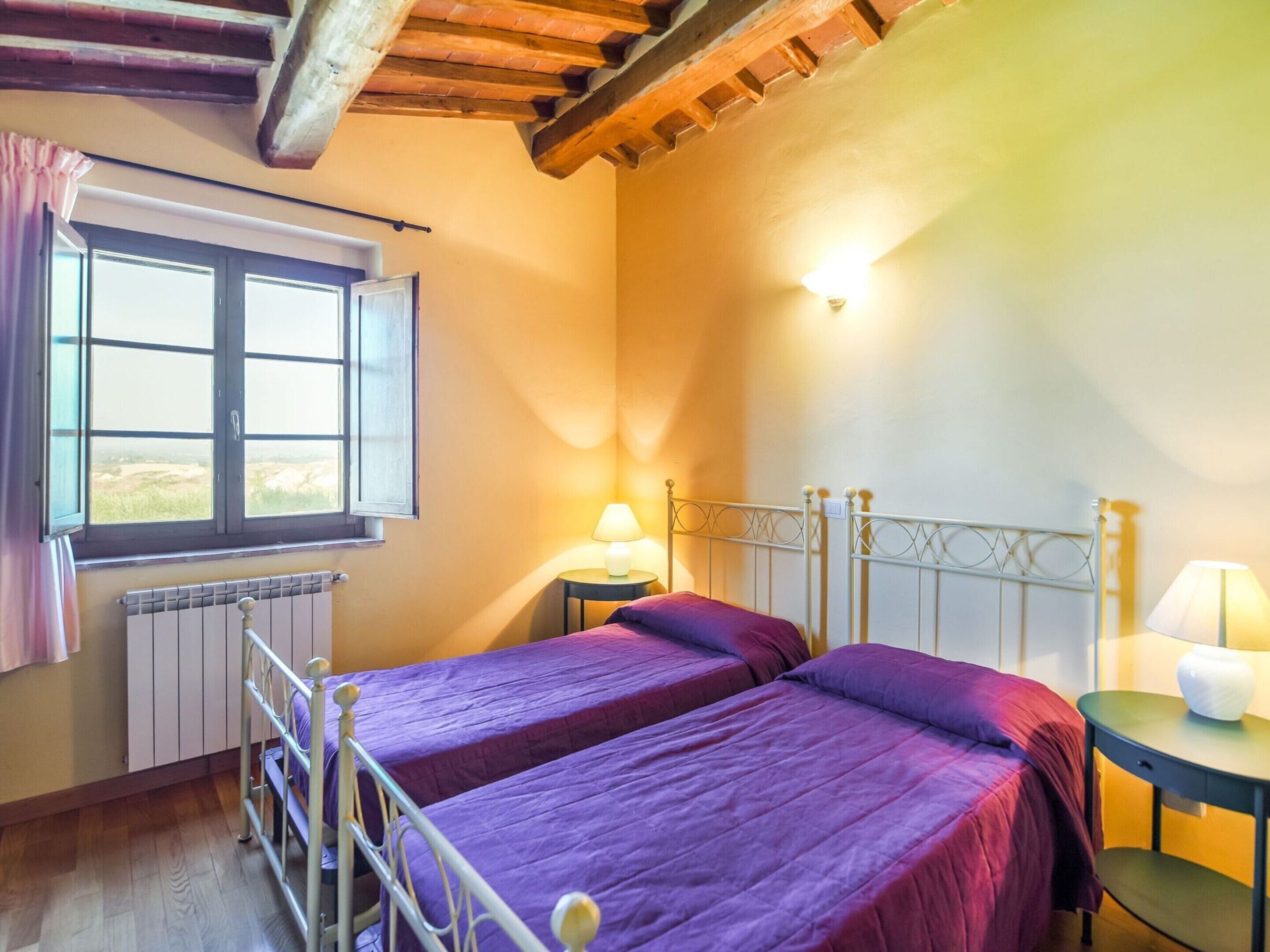 Une chambre avec deux lits, une fenêtre, un radiateur et une lampe.