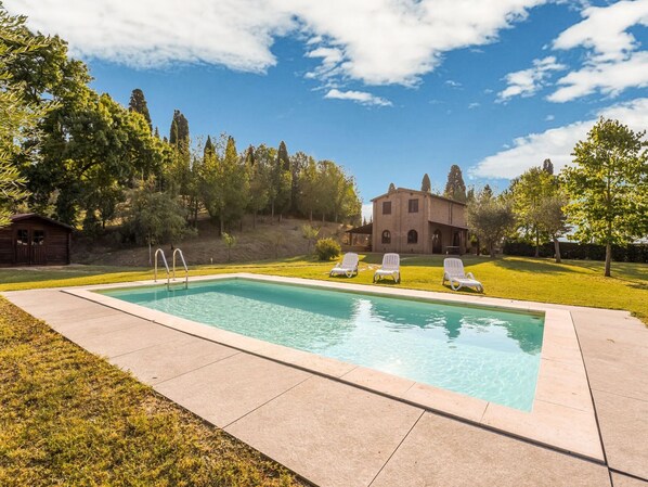 A rectangular swimming pool with three white lounge chairs, a wooden cabin, and a stone building in a landscaped garden. - Private Garden and Pool, Near Siena and Crete Senesi (Asciano)