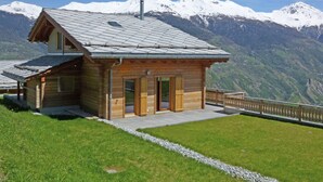 A wooden mountain lodge with a sloped roof, a wooden door, and a stone pathway leading to the entrance. - Chalet in Heremence With Stunning Alpine Views (Heremence)
