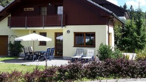 A two-story chalet with a balcony, outdoor seating, and a sign indicating a restaurant. - Villa by Lake & Slopes (Lipno nad Vltavou)