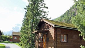 A wooden cabin with a porch, surrounded by lush greenery and mountains in the background. - Holiday Home in Nysted by Baltic Sea (Saas-Balen)