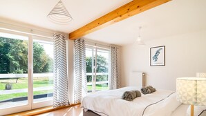 A bedroom with a bed, a bedside table, a lamp, and a window with curtains. - Luxurious Villa With Pool and Sauna, and Very Suitable for Culinary Workshops (Waimes)